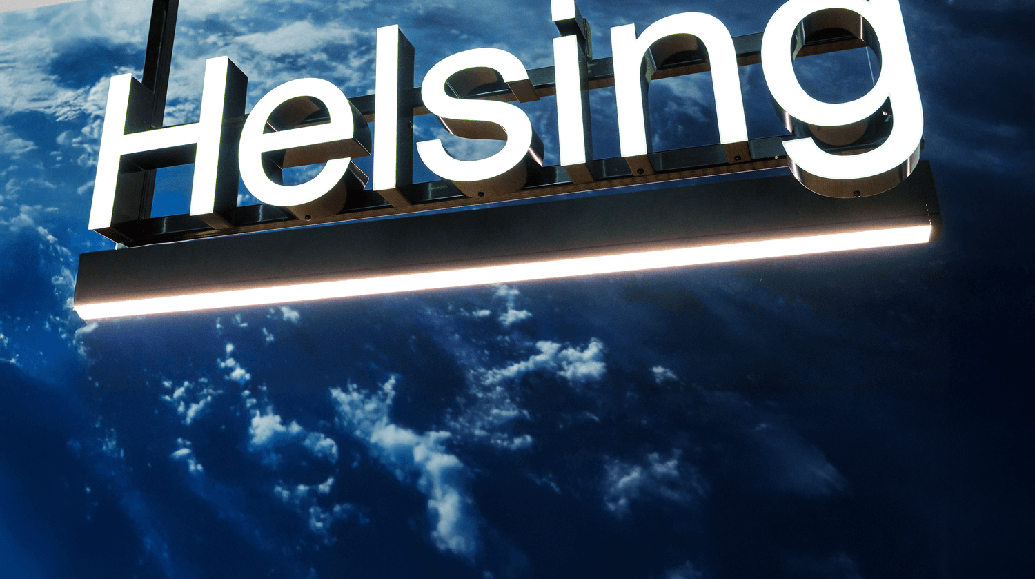 An illuminated sign of the Helsing logo